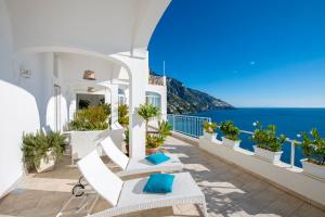 Un balcón con sillas blancas y vistas al océano. en Casa Fioravante, en Positano
