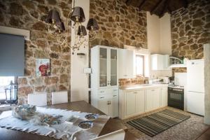 a kitchen with a table and a stone wall at Stone Villas in Nea Roda