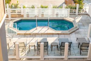 a swimming pool with tables and chairs next to it at Beachfront Inn and Suites at Dana Point in Capistrano Beach