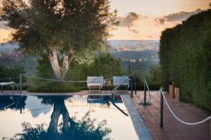 a swimming pool with two chairs and a tree at Hotel Villa Favorita in Noto