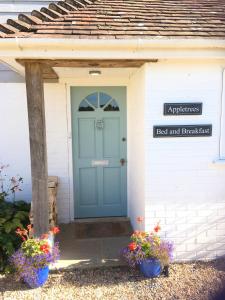 a blue door on a white house with flowers at Appletrees B&B in Midhurst