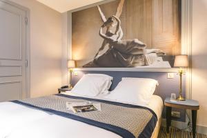 ein Hotelzimmer mit einem Bett mit einem Gemälde an der Wand in der Unterkunft Hotel Saint Christophe in Paris