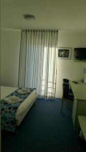 een hotelkamer met een bed, een bureau en een raam bij Les Balcons Du Velay in Monistrol-sur-Loire