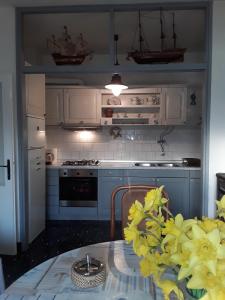 a kitchen with white cabinets and a table with yellow flowers at Adorable Summer house by the sea in Zapuntelo