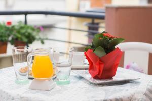 a table with glasses of orange juice and a vase of flowers at B&B Ulisse in Ispica