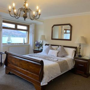 Dormitorio con cama con espejo y lámpara de araña en Westcourt Bed & Breakfast, en Fort William