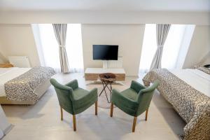 a bedroom with two beds and two chairs and a television at The Corner Inn Hotels By Suit in Eskisehir