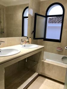 エステポナにあるVillacana 31/17のバスルーム(洗面台2台、バスタブ付)、窓が備わります。