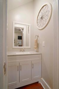 La salle de bains est pourvue d'un lavabo blanc et d'un miroir. dans l'établissement 414 Waldburg A · Newly Renovated Apt with outdoor space!, à Savannah