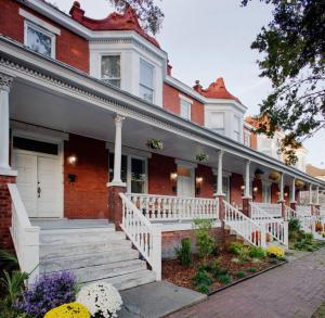 une maison en briques rouges avec une terrasse couverte blanche et des escaliers. dans l'établissement 414 Waldburg A · Newly Renovated Apt with outdoor space!, à Savannah