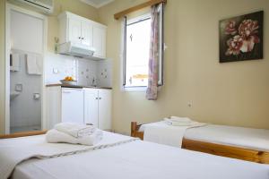 Habitación con 2 camas y cocina con ventana en Kantouni Apartments, en Svoronata