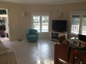 a living room with a tv and a blue chair at Casa Pauline in Benissa