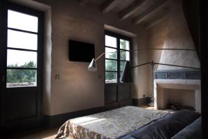 a bedroom with a bed and a tv and two windows at B&B La Fustaia in Sarzana
