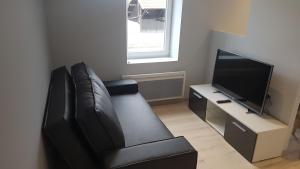 un soggiorno con divano in pelle nera e TV di Appartement T2 proche gare et centre Bourgoin a Bourgoin