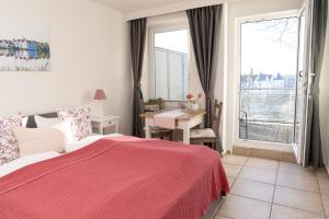een slaapkamer met een bed met een rode deken en een raam bij Hotel am Wasserschloss Glücksburg in Glücksburg