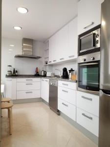 una cocina con armarios blancos y electrodomésticos de acero inoxidable en SEA ONE. en Port de Pollensa