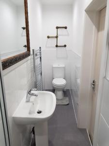 a white bathroom with a toilet and a sink at The Snug at Plover Cottage Lindley in Huddersfield