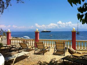a group of chairs sitting in front of the ocean at Apartments Corfu Sun Sea Side in Benitses