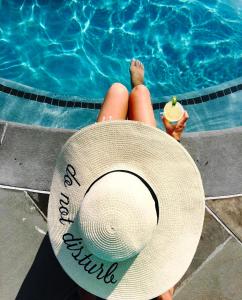 a woman in a straw hat next to a swimming pool at Pacific Terrace Hotel in San Diego