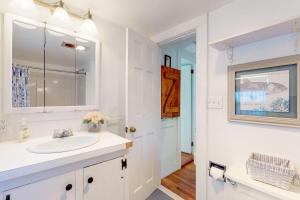 a white bathroom with a sink and a mirror at Little Cozy Corner in Edgartown