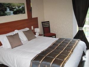 a bedroom with a large white bed with a suitcase on it at Hotel Restaurant Rive Gauche in Bessines-sur-Gartempe