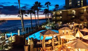 a hotel with a swimming pool and the ocean at night at Pacific Terrace Hotel in San Diego
