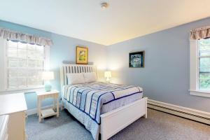 a blue bedroom with a bed and two windows at Vineyard Charm in Edgartown