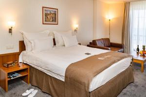 a hotel room with a large bed and a chair at Panorama Hotel - Free EV Charging Station in Varna City