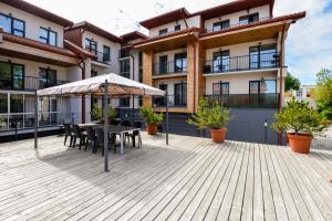 una terrazza in legno con tavolo e ombrellone di Tatjanos apartamentai a Palanga