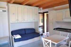 a living room with a blue couch and a kitchen at Palm Village in Villasimius