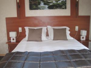 a bedroom with a bed with white sheets and pillows at Hotel Restaurant Rive Gauche in Bessines-sur-Gartempe