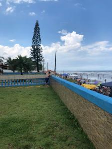eine Person mit Sonnenschirm und Blick über eine Mauer am Strand in der Unterkunft Apartamento pé na areia in Itanhaém