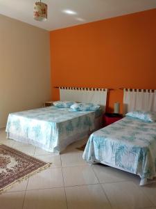 2 Betten in einem Zimmer mit orangefarbenen Wänden in der Unterkunft Apartamento Elite em Cunha in Cunha