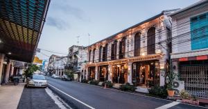 eine Stadtstraße mit Gebäuden und einem Auto auf der Straße in der Unterkunft สงขลาแต่แรก แอนทีค โฮเท็ล Songkhla Tae Raek Antique Hotel in Songkhla