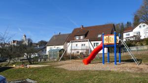 a playground with a red slide in a yard at guest apartment niederalfingen in Hüttlingen