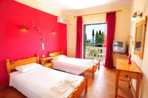 a room with two beds and a red wall at Apartments Corfu Sun Pool Side in Benitses