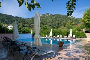 een zwembad van het resort met stoelen en parasols bij Apartments Corfu Sun Pool Side in Benitses