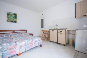 a bedroom with a bed and a desk and a kitchen at Holiday Home Ratac Sunshine Beach in Slano