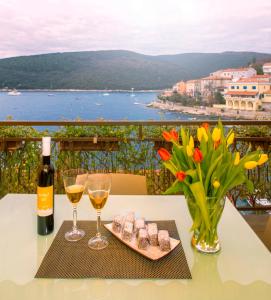 a table with two glasses of wine and a vase of flowers at Carli in Rabac
