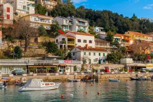 a small boat in a body of water with buildings at Carli in Rabac