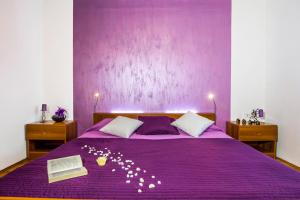 a purple bed with a purple wall with a flower arrangement on it at Carli in Rabac