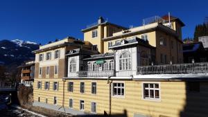 un grand bâtiment jaune avec de la neige sur le toit dans l'établissement Astoria Apartments, à Schruns