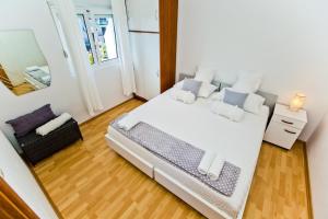1 dormitorio con 1 cama blanca grande y espejo en Apartments Ana I, en Hvar