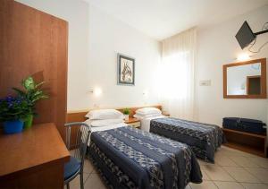a hotel room with two beds and a desk at Hotel Jana in Rimini