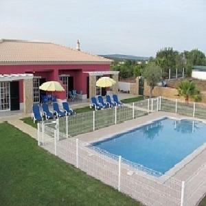 a swimming pool with chairs and umbrellas next to a house at Vila da Mesa in Algoz