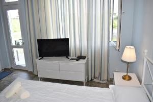 a bedroom with a television on a dresser with a bed at Синя луна in Lozenets