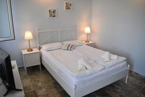 a bedroom with a bed with white sheets and two lamps at Синя луна in Lozenets