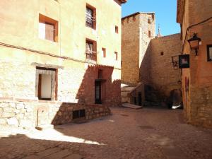 Une allée dans un vieux bâtiment avec une tour dans l'établissement Apartamento Portal de Molina, à Albarracín