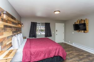 um quarto com uma cama vermelha e uma televisão de ecrã plano em Apple Creek Cottages em Prescott