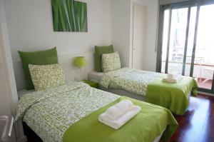 ein Schlafzimmer mit zwei Betten mit grüner Bettwäsche und einem Fenster in der Unterkunft Happy Holiday Beach Home in Sitges